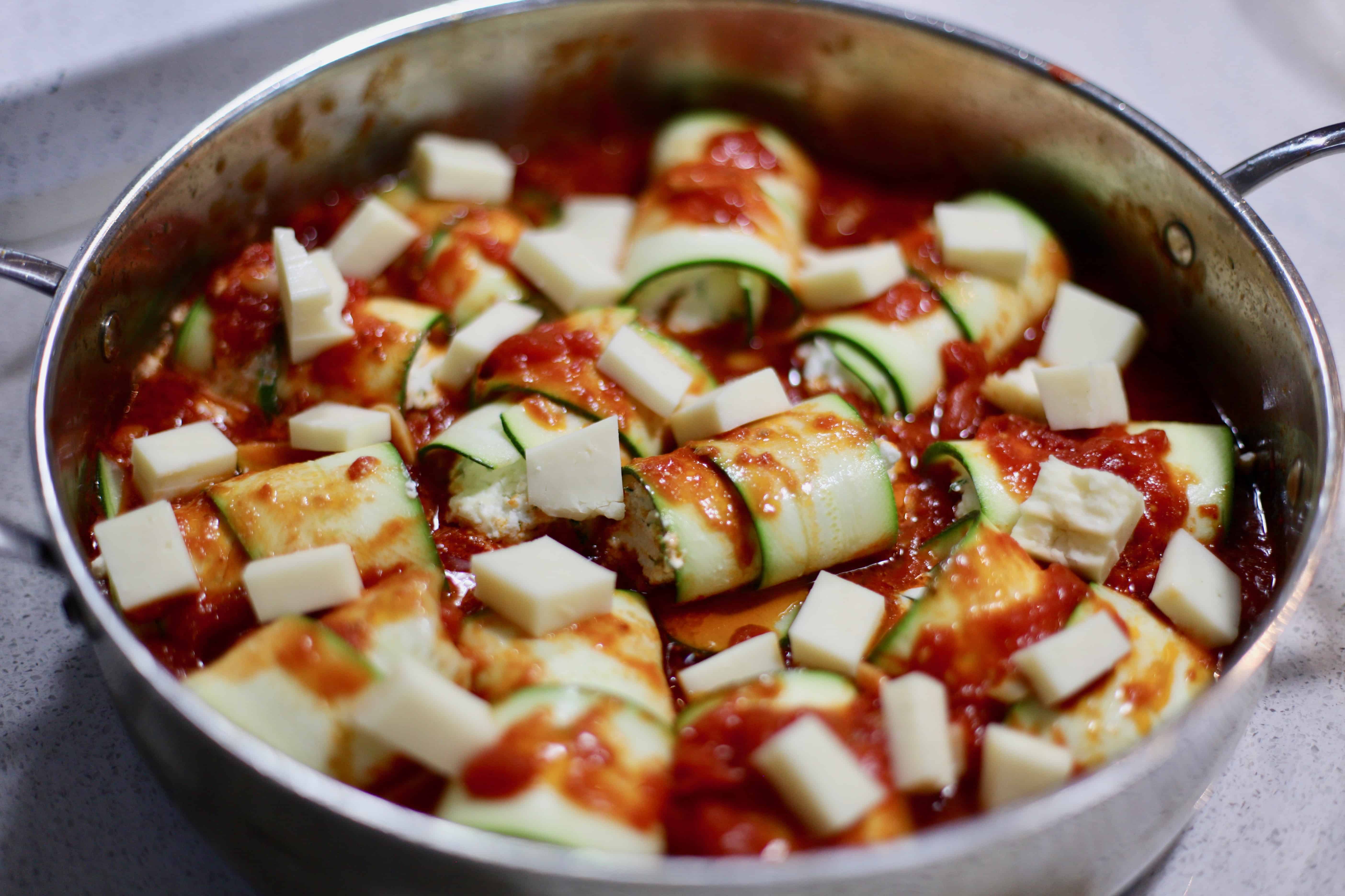 zuchinni rolls prepped in sauce for the oven